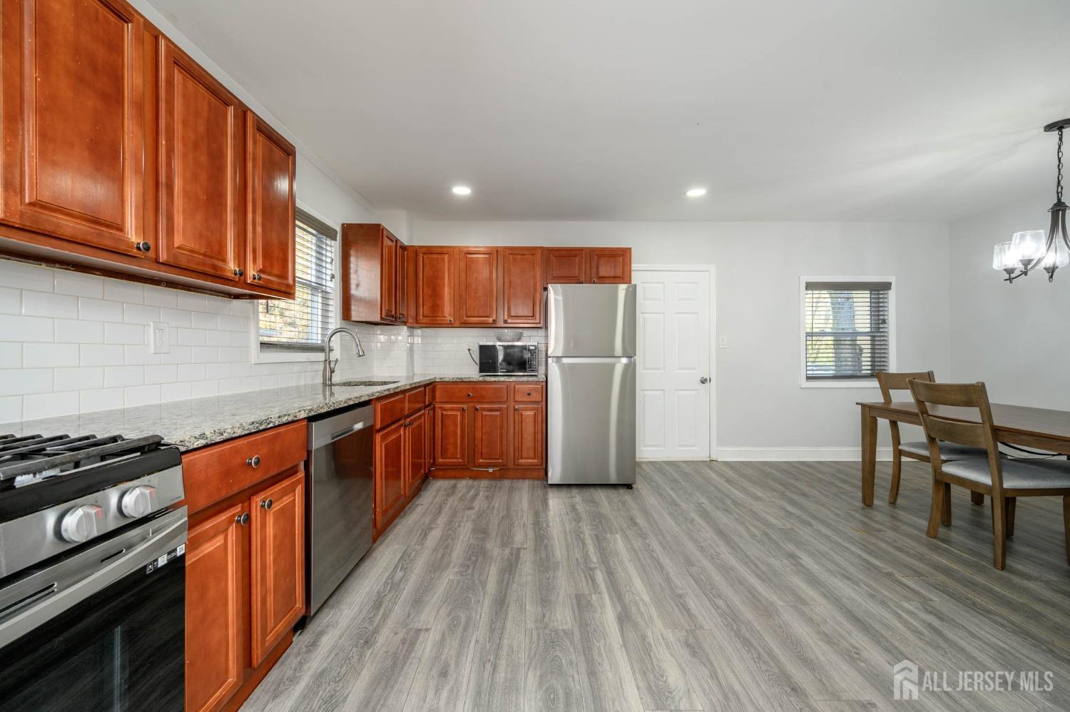 32 Lee Street Port Reading, NJ 07064 - Photo 7 of 32 a kitchen with stainless steel appliances granite countertop a refrigerator a stove top oven a sink dishwasher and cabinets with wooden floor