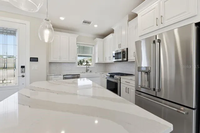 a kitchen with stainless steel appliances granite countertop a refrigerator sink stove microwave and cabinets