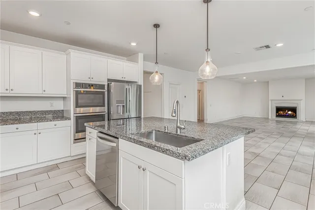 a kitchen with stainless steel appliances granite countertop a sink a stove a refrigerator and white cabinets with granite countertops