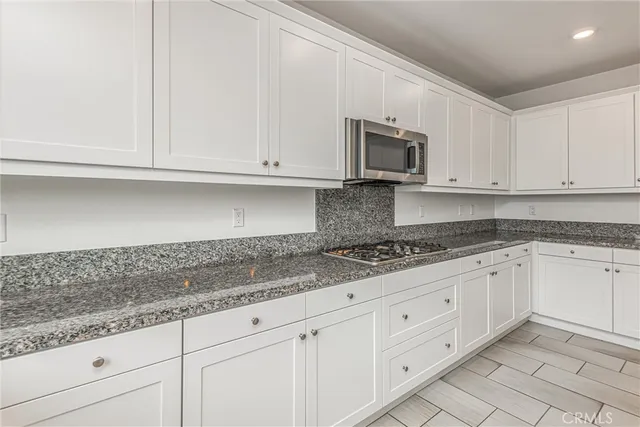 a kitchen with granite countertop white cabinets and a sink