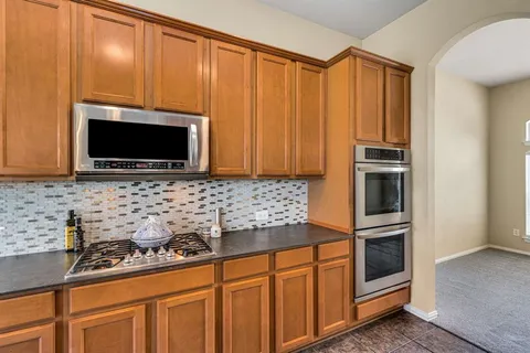 a kitchen with granite countertop a sink stove and microwave