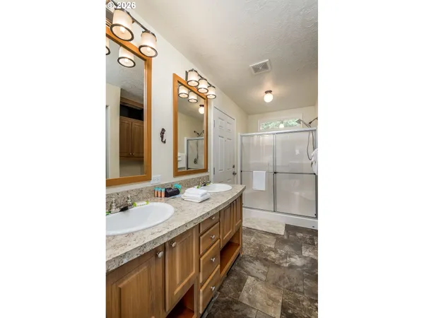 a spacious bathroom with a double vanity sink a mirror and a shower
