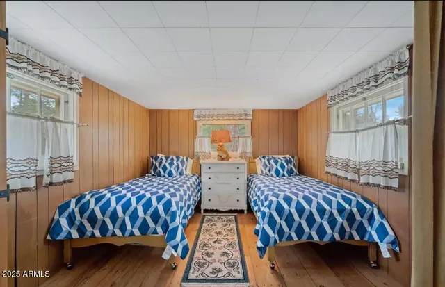 a bedroom with two beds and wooden floor