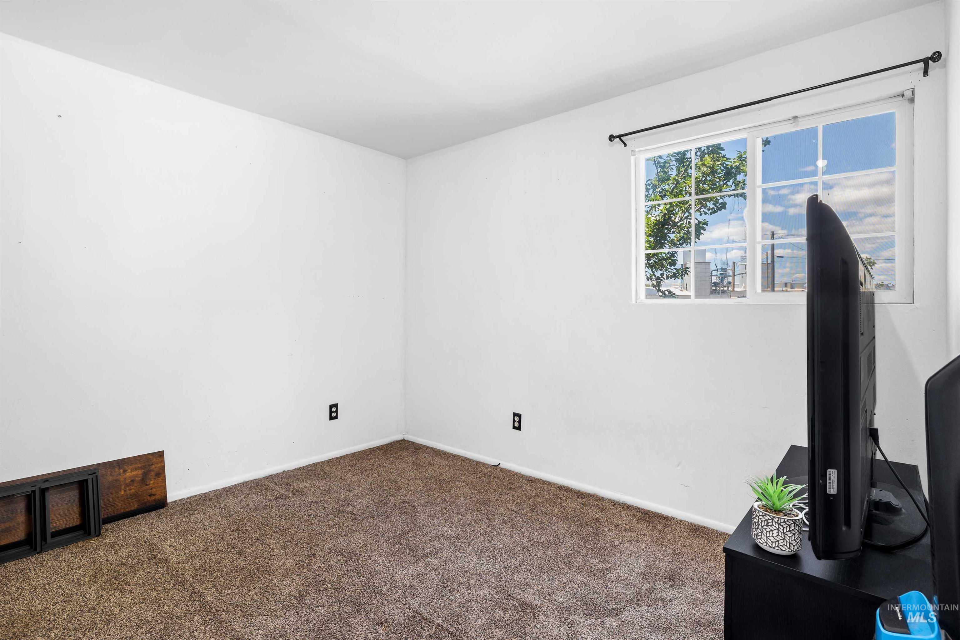 102 East 6th Street Rupert, ID 83350 - Photo 12 of 27 Carpeted interior space featuring white walls, a single window with white framing and grid patterns, and a dark curtain rod
