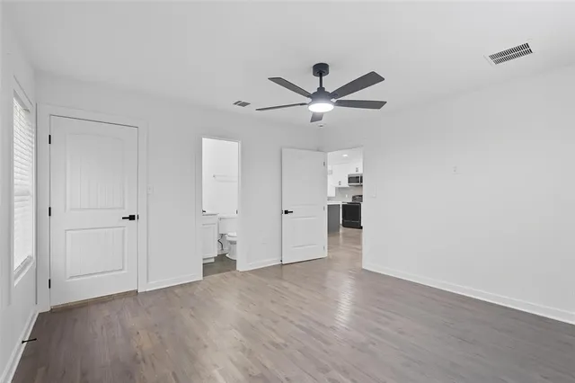 an empty room with wooden floor and ceiling fan