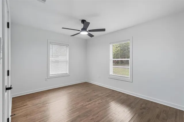 a view of an empty room with a window and wooden floor
