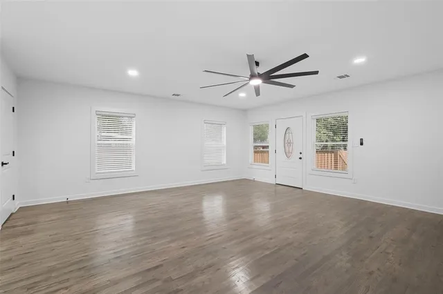 a view of an empty room with a window and wooden floor