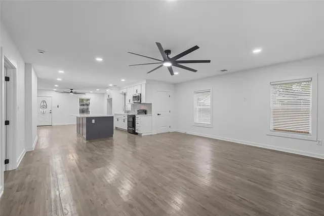 a view of an empty room with a window and wooden floor