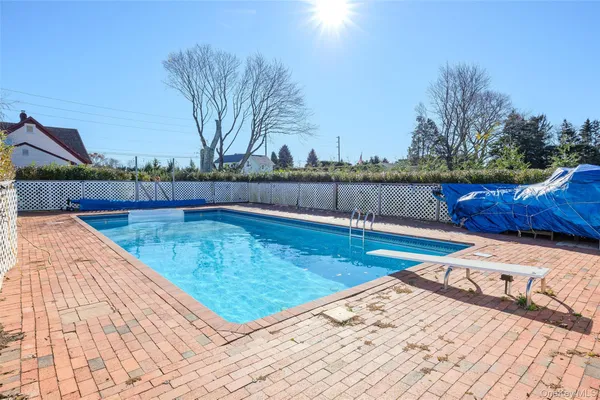 a view of swimming pool with seating space and trees in the background