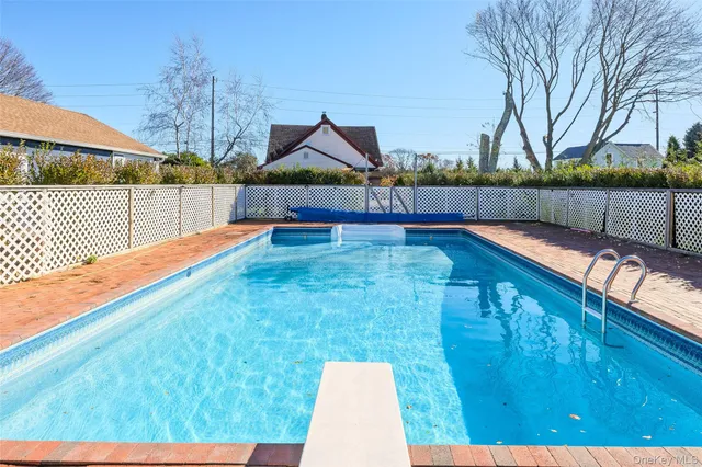 a view of swimming pool with seating space and trees in the background