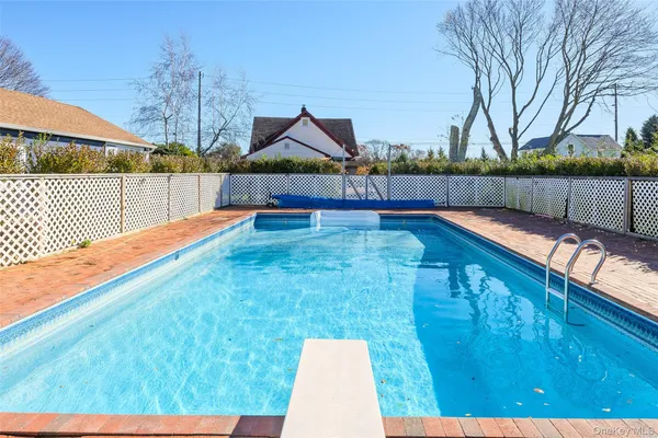 a view of swimming pool with seating space and trees in the background