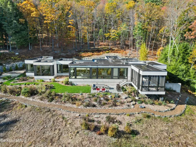 an aerial view of a house with a yard lake and outdoor seating