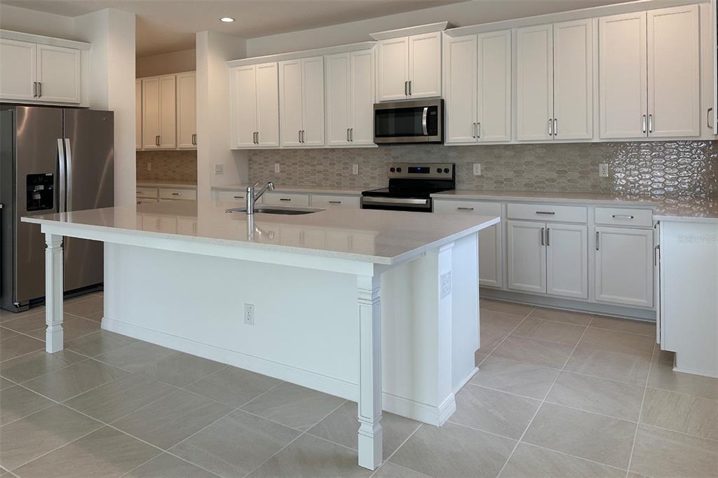 761 Farfields Street DeLand, FL 32724 - Photo 4 of 11 a kitchen with stainless steel appliances granite countertop a refrigerator sink and white cabinets