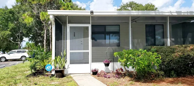 a view of a house with potted plants and a bench