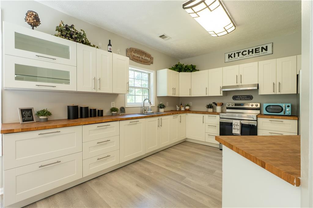 2238 St Albans Place Buford, GA 30519 - Photo 13 of 56 a kitchen with granite countertop white cabinets and white appliances