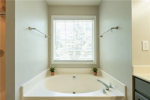 a bathroom with a double vanity sink a large mirror and a bathtub