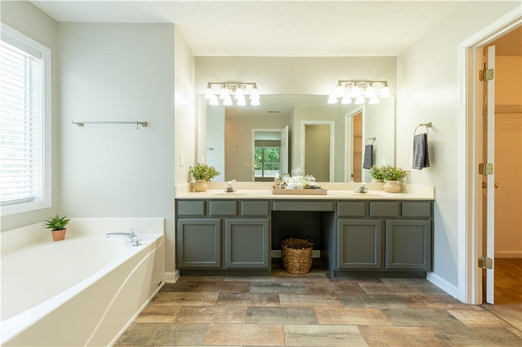 2238 St Albans Place Buford, GA 30519 - Photo 40 of 56 a bathroom with a tub a double vanity sink and mirror