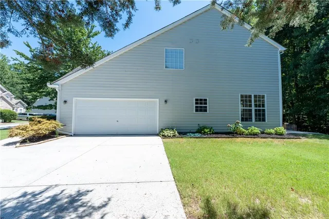 a backyard of a house with large trees and plants