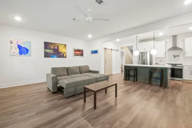 a living room with stainless steel appliances furniture and wooden floor