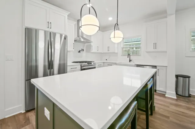 a kitchen with a table a sink a refrigerator and wooden floor