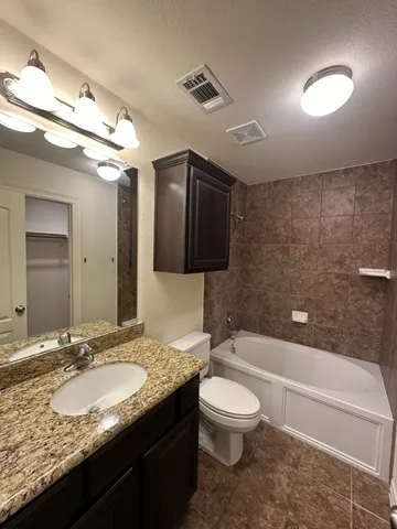 a bathroom with a granite countertop sink a toilet and bathtub