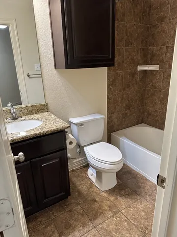 a bathroom with a granite countertop toilet sink and mirror