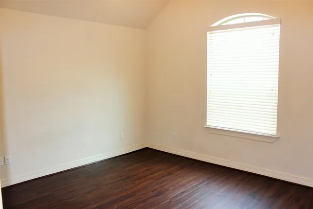an empty room with wooden floor and window