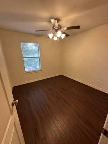 a view of a room with wooden floor and a ceiling fan