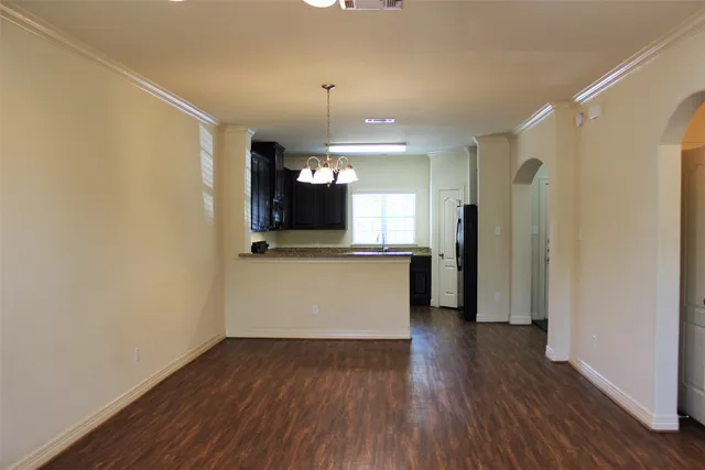 a view of a hallway with wooden floor and a kitchen