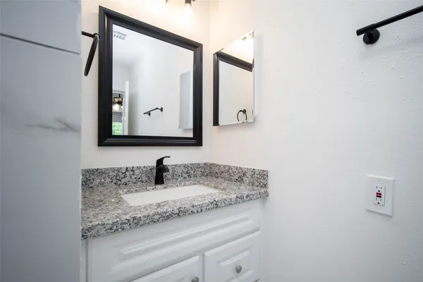 a bathroom with a granite countertop sink and a mirror