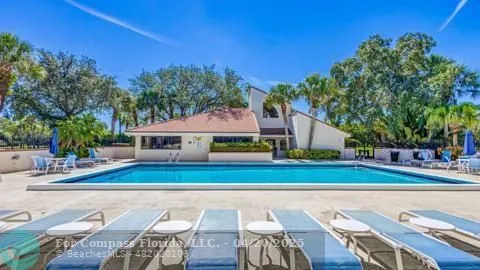 a view of swimming pool with lawn chairs and plants