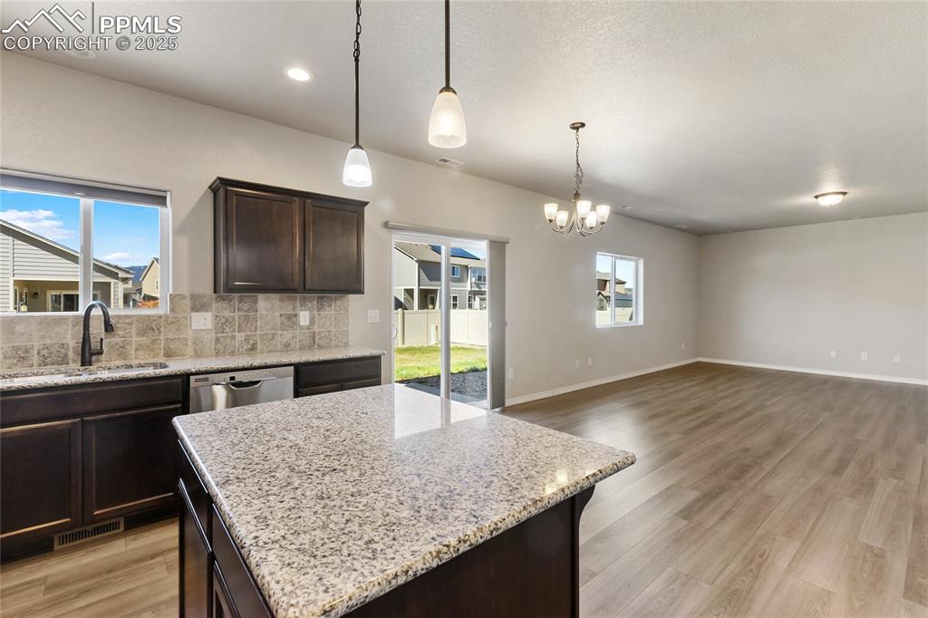 10858 Traders Parkway Fountain, CO 80817 - Photo 12 of 38 a kitchen with kitchen island granite countertop a stove a sink a center island and wooden floor