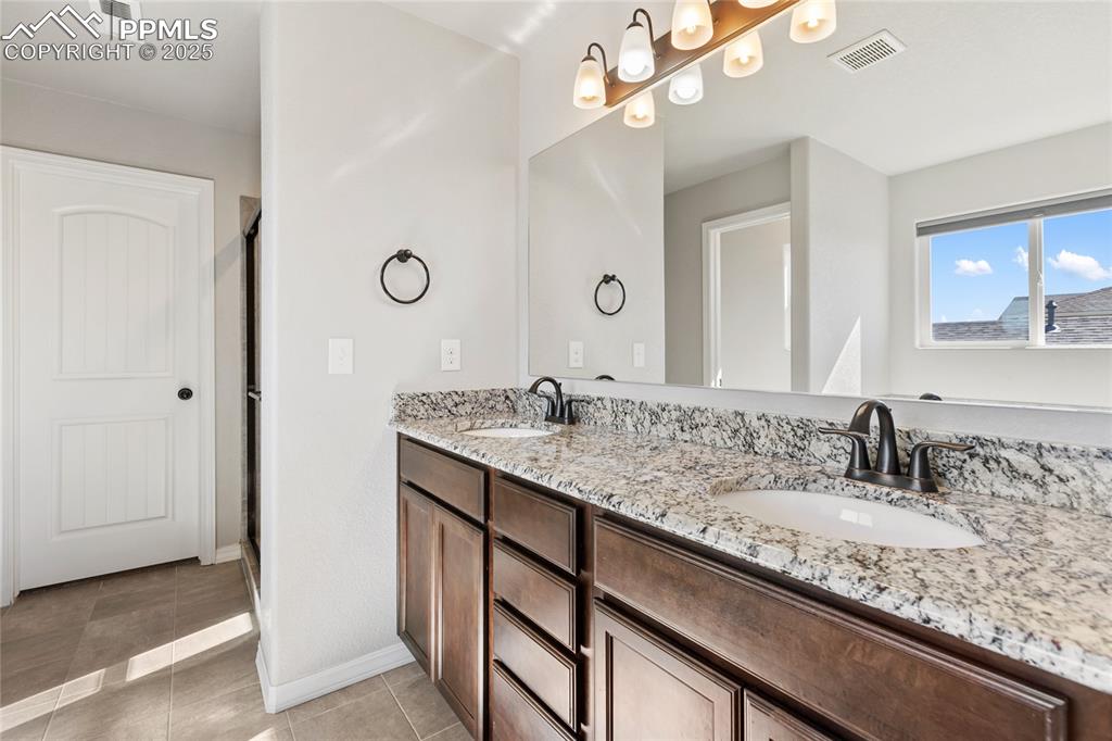 10858 Traders Parkway Fountain, CO 80817 - Photo 24 of 38 a bathroom with a granite countertop sink a large mirror and a shower
