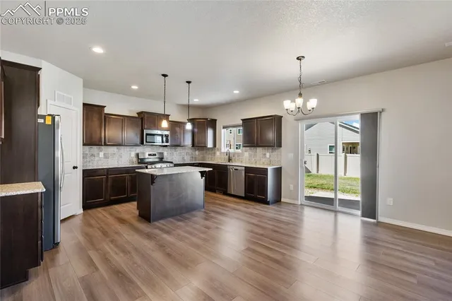 a large kitchen with a wooden floor stainless steel appliances and cabinets