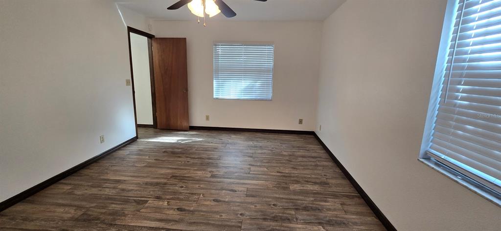10605 Southwest 68th Terrace Ocala, FL 34476 - Photo 16 of 20 an empty room with wooden floor chandelier fan and windows