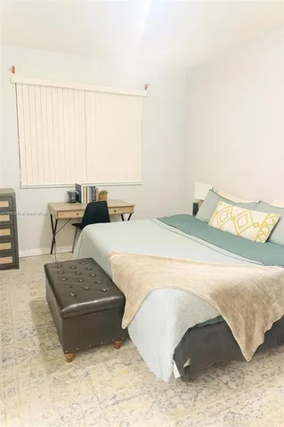 a spacious bedroom with a bed a couch and large window