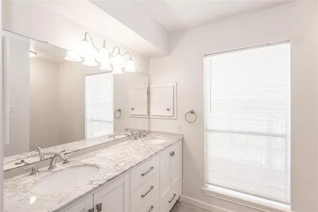a bathroom with a granite countertop sink a mirror and a shower