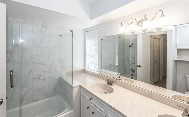 a bathroom with a sink vanity granite tub shower and a mirror