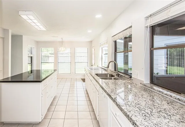 a large white kitchen with kitchen island granite countertop a large window