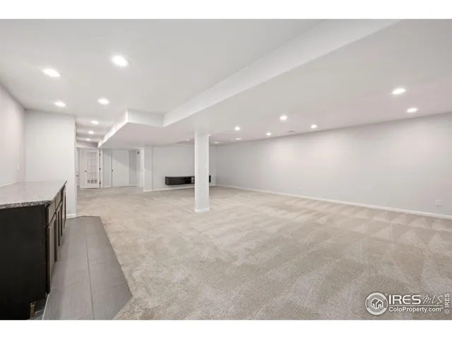 a view of an empty room with kitchen and a window