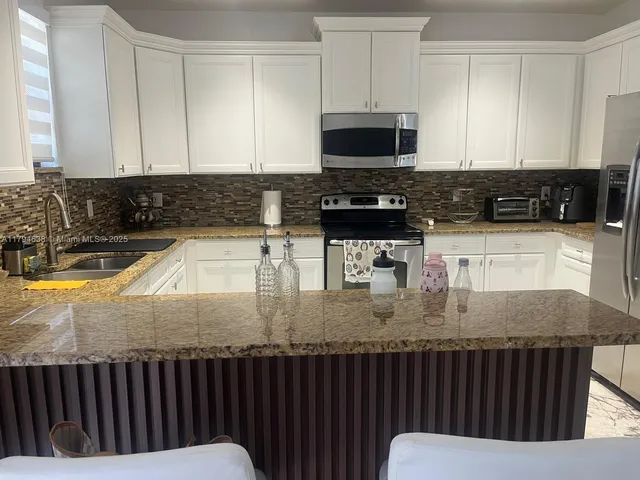 a kitchen with a sink a microwave a stove and cabinets