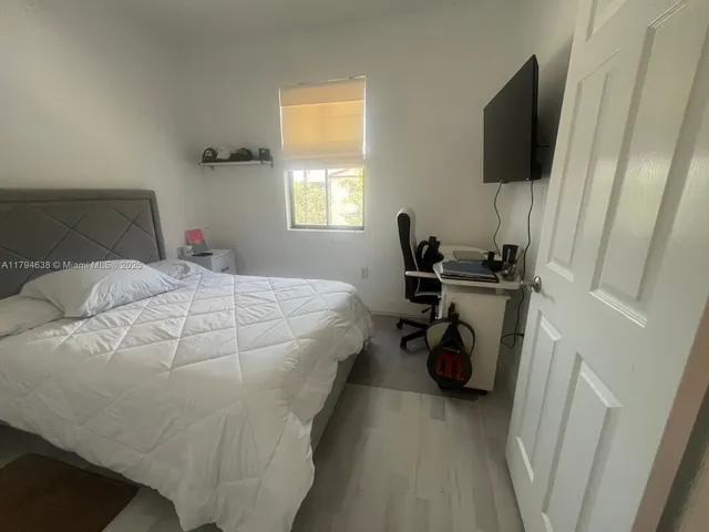 a bedroom with a bed and a flat tv screen on the dresser
