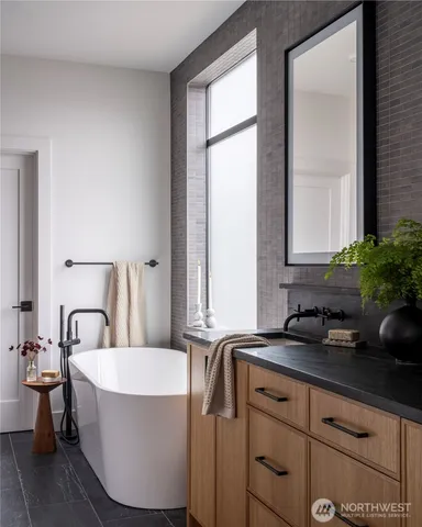 a bathroom with a granite countertop sink a mirror and a bathtub