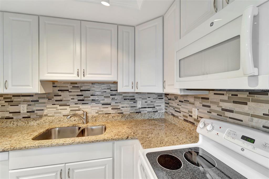 5855 Midnight Pass Road, Unit 314 Sarasota, FL 34242 - Photo 21 of 58 a kitchen with granite countertop white cabinets and white appliances