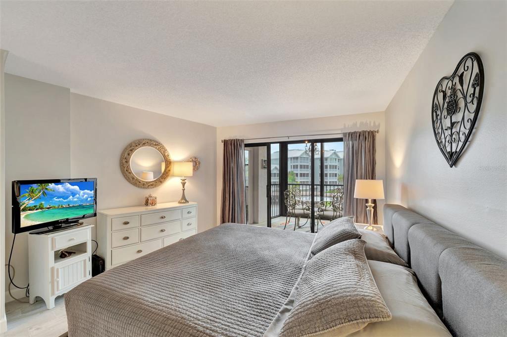 5855 Midnight Pass Road, Unit 314 Sarasota, FL 34242 - Photo 25 of 58 a spacious bedroom with a bed and a flat screen tv