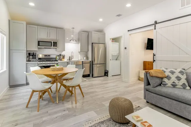a living room with stainless steel appliances furniture and a wooden floor
