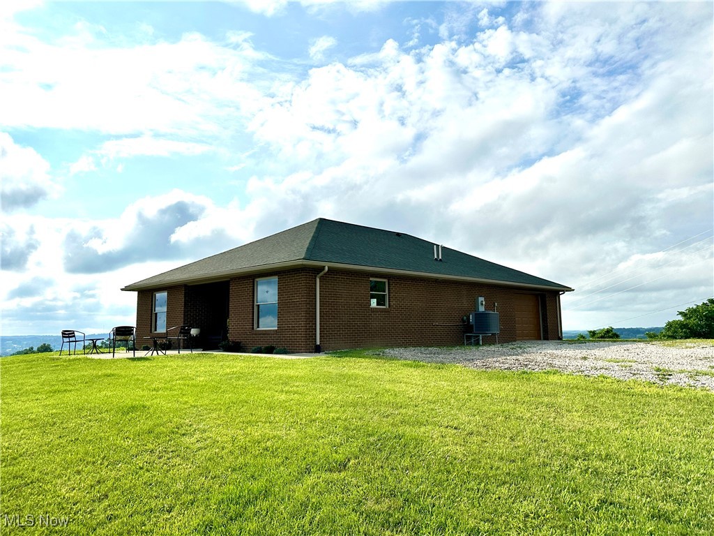 18331 Davis Ridge Road Caldwell, OH 43724 - Photo 4 of 31 View of home's exterior with brick siding, a yard, and a garage