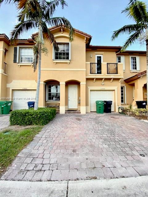 12999 Southwest 132nd Terrace, Unit 12999 Miami, FL 33186 - Photo 1 of 23 a front view of a house with a yard and a garage