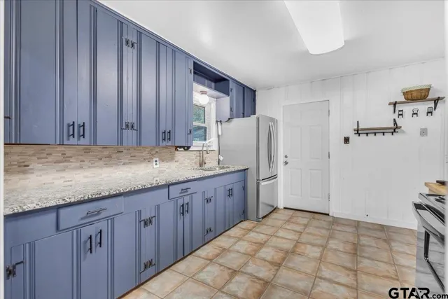 a kitchen with granite countertop wooden cabinets a refrigerator and a sink