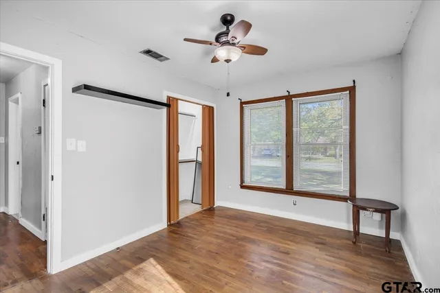 a view of an empty room with a window and wooden floor